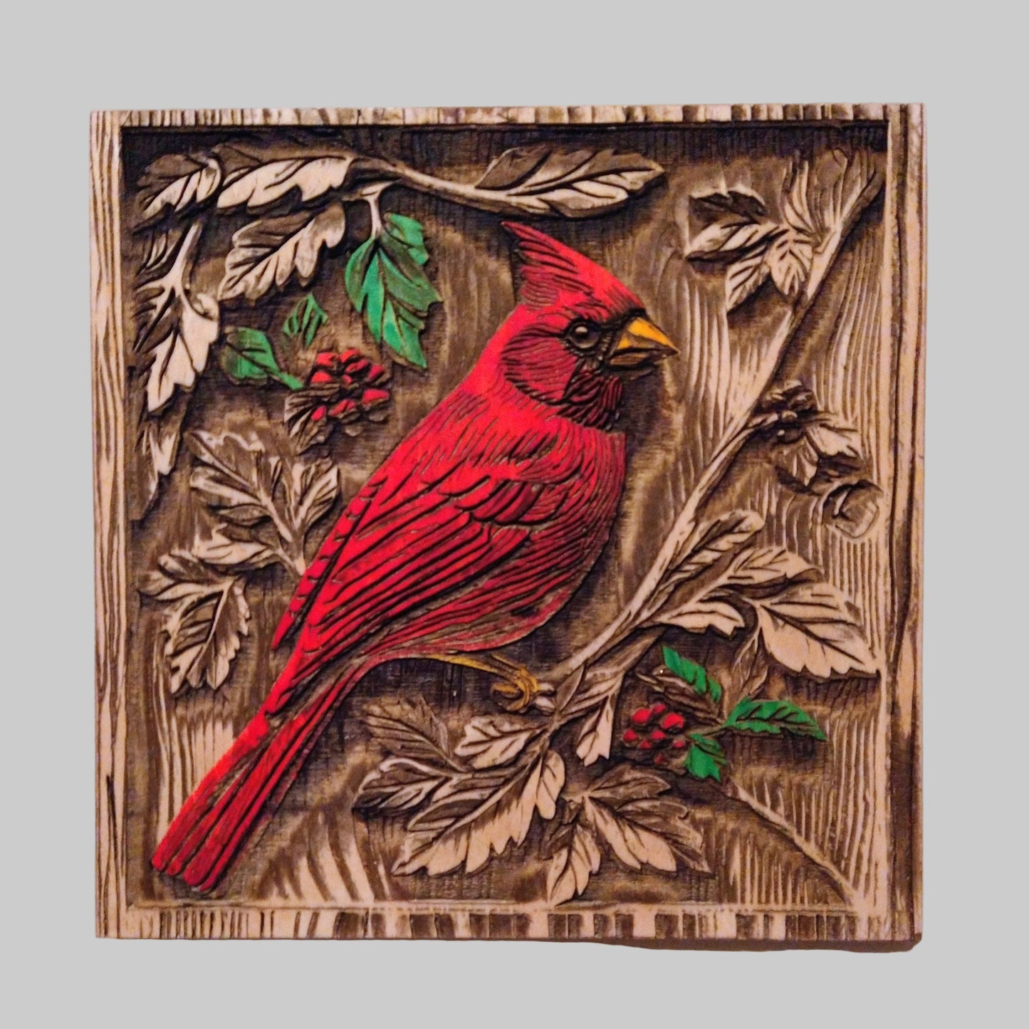 Wooden wall art with a red cardinal bird and nature elements on a white background