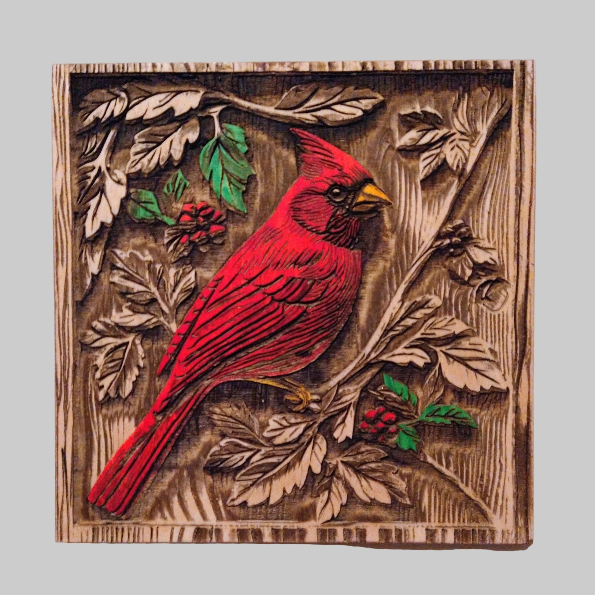 Wooden wall art with a red cardinal bird and nature elements on a white background